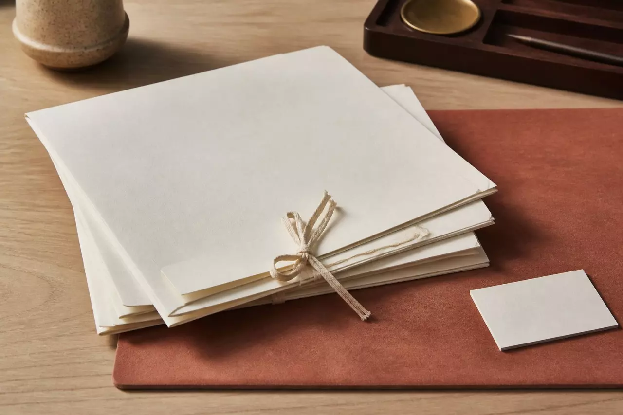 Chemise de manuscrits et carte de visite d’agent sur un bureau de bois clair.